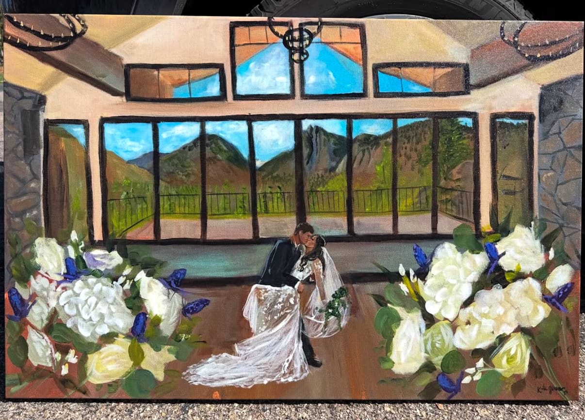 Live wedding painting of a bride dipping during a kiss with the groom inside a rustic pavilion venue featuring floor-to-ceiling windows and mountain views in Estes Park, CO